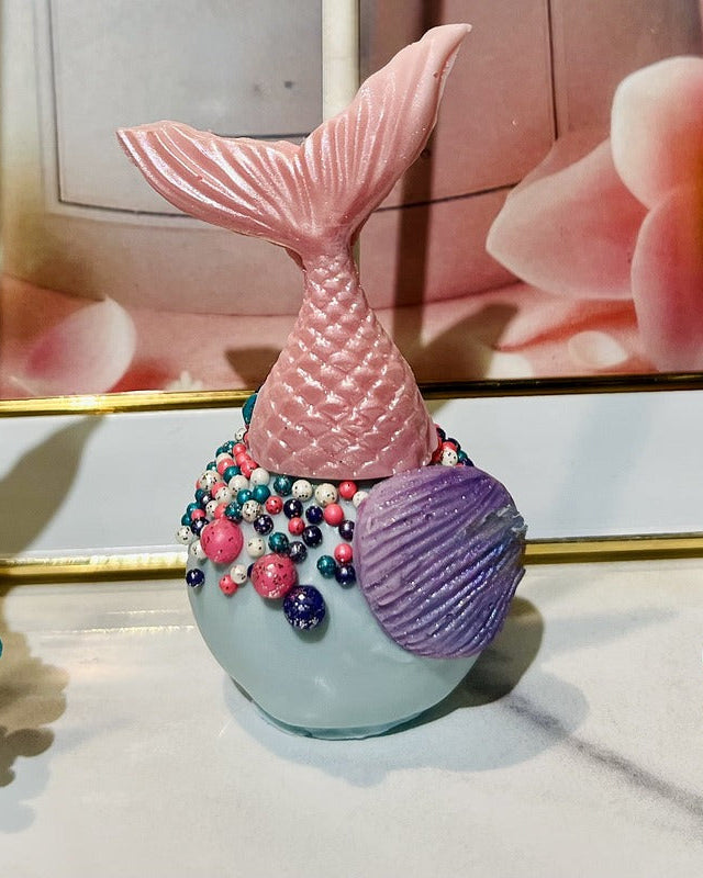 Three decorative mermaid tail figurines with colorful beads on a surface cake pop.